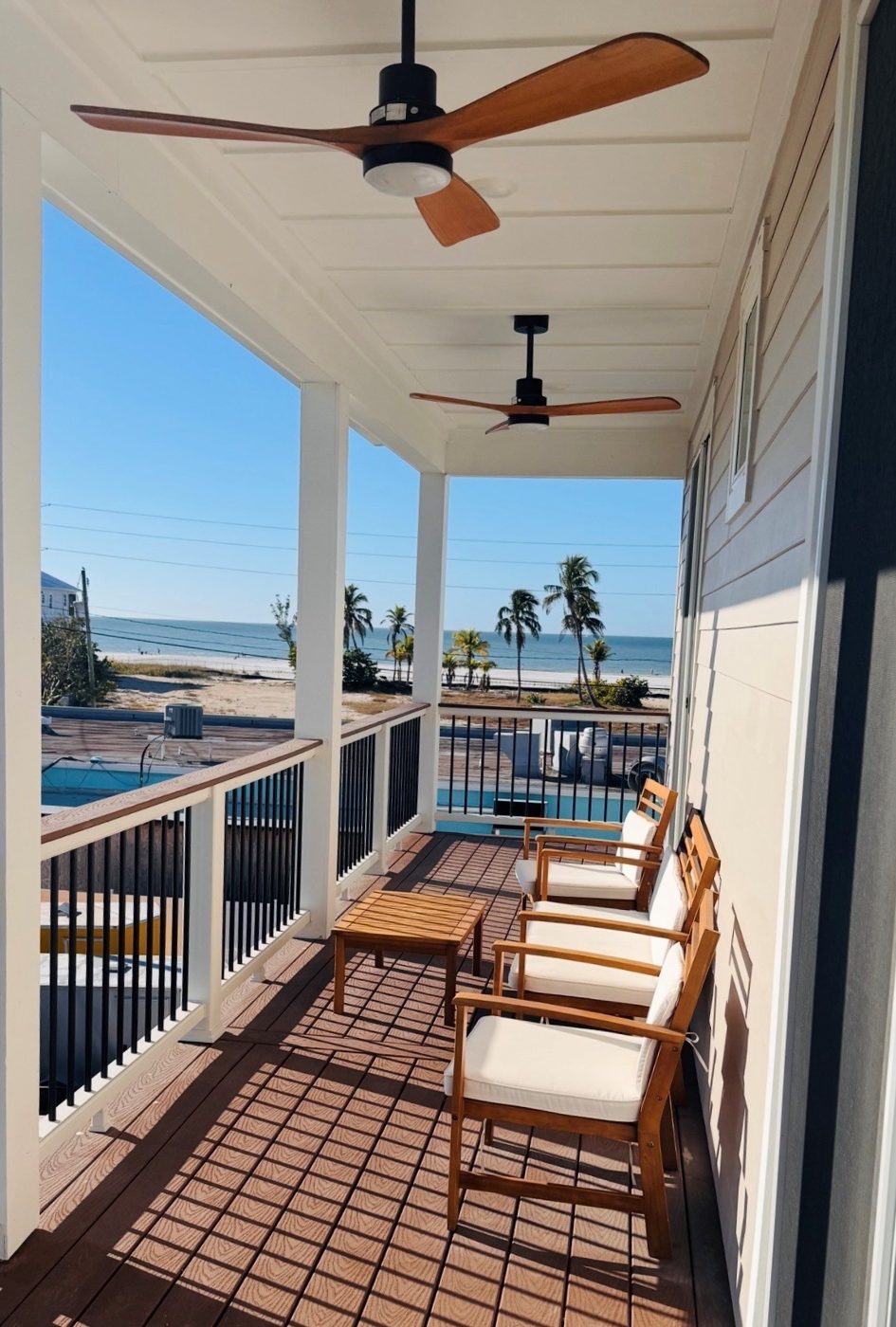 Covered balcony with ceiling fans, seating, and Gulf of Mexico views at Do We Beach House